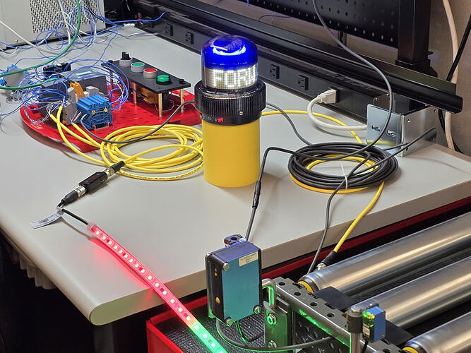 Benchtop view of a conveyor section with Banner beacon and Siemens ET 200 in the background.
